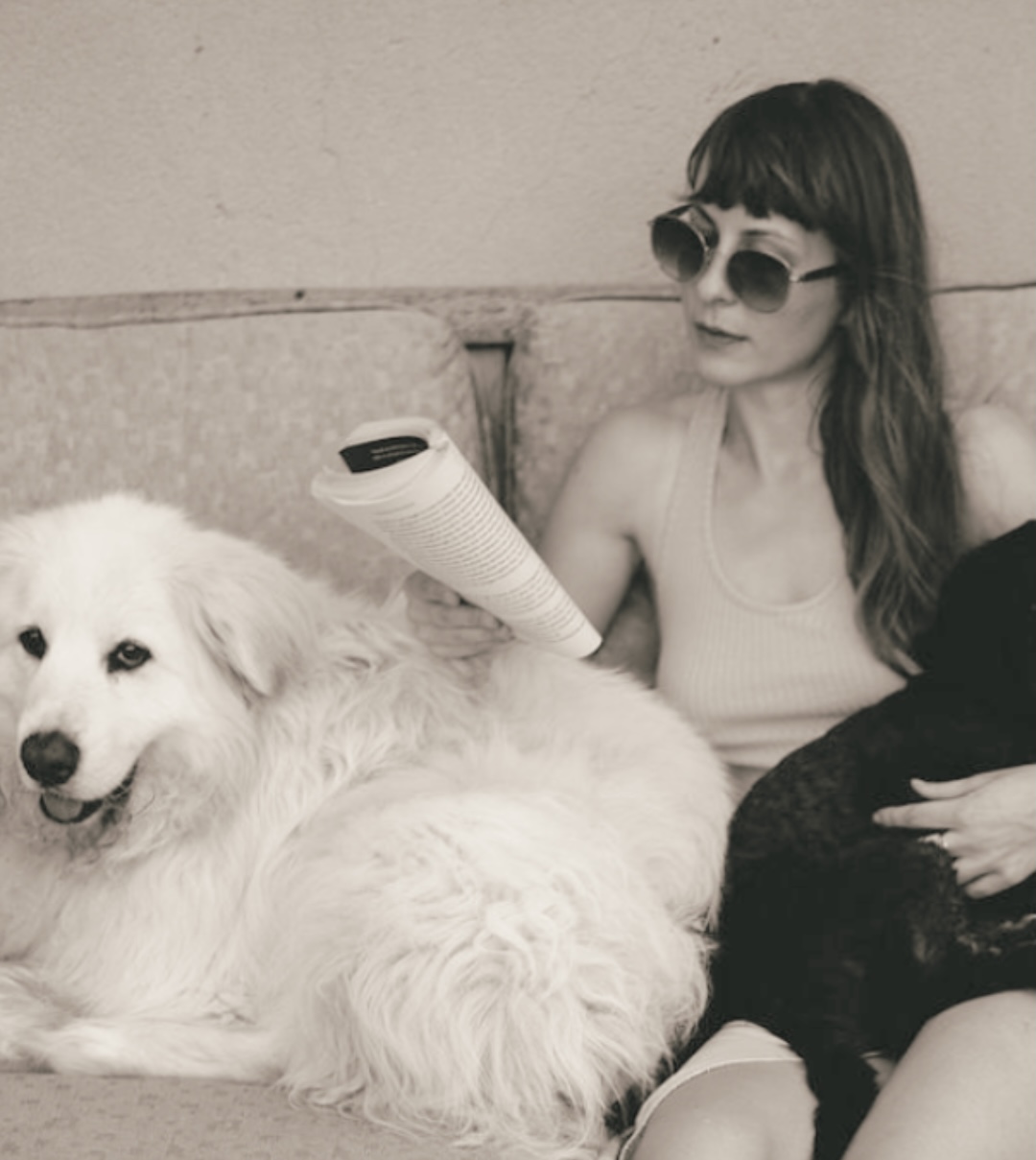 Martyna reading beside two rescued dogs